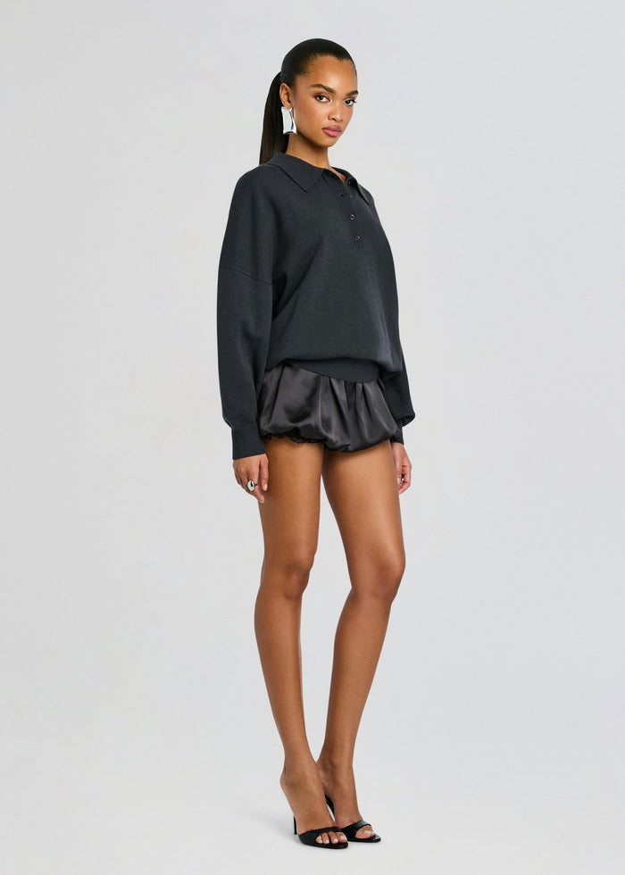 Full body of a model in a dark oversized polo and Misha Short satin shorts with lace trim, wearing black heeled sandals. media 4 of 5