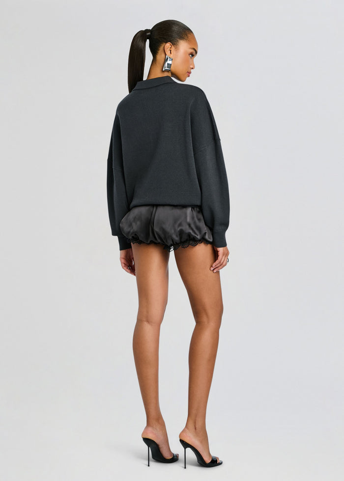 Back view of a model wearing the Misha Short outfit: oversized dark knit top with satin lace-trim shorts and heels. media 5 of 5