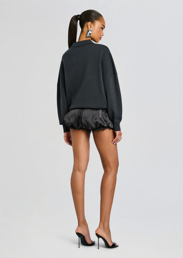 Back view of a model in a dark Vespen Sweater with oversized fit paired with satin shorts.