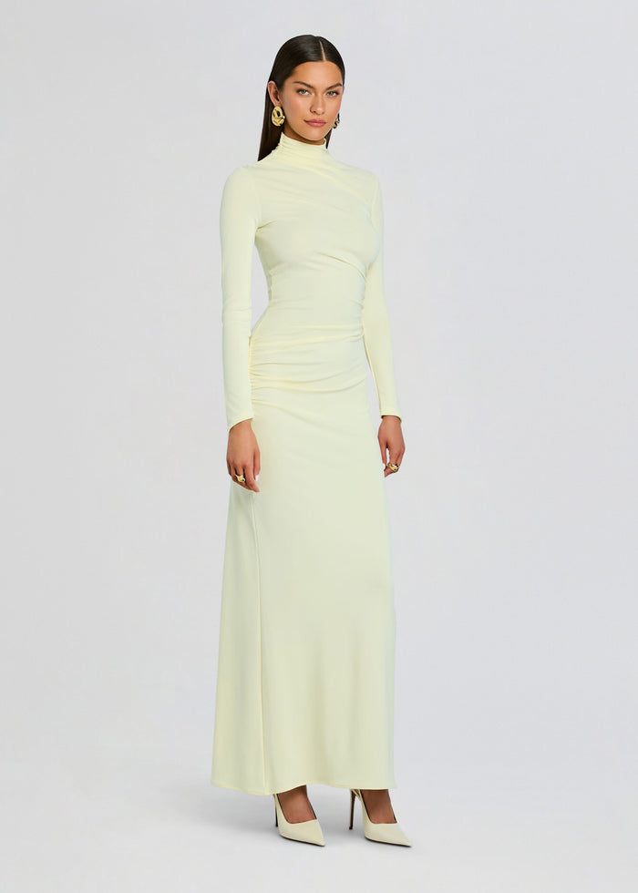 Full-length view of a model wearing the pale yellow Oona Maxi Dress with a high neck and fitted silhouette media 3 of 5