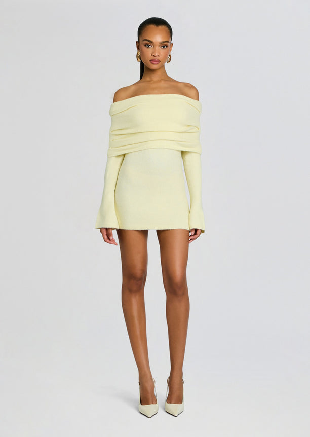 Full-body view of a model in a pale yellow off-shoulder knit mini dress with long sleeves and heels