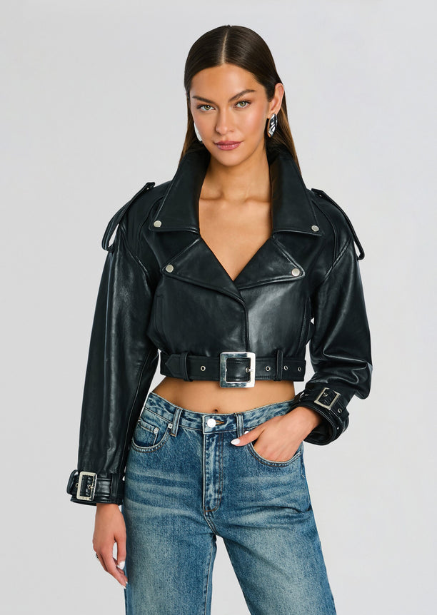 Model in a black cropped leather jacket with a belt paired with blue jeans