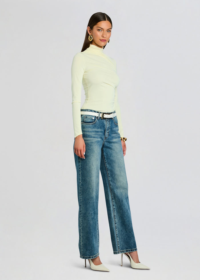 Model wearing pale yellow Vivienne Top with a turtleneck, paired with high waist jeans, a white belt, and cream heels media 4 of 5