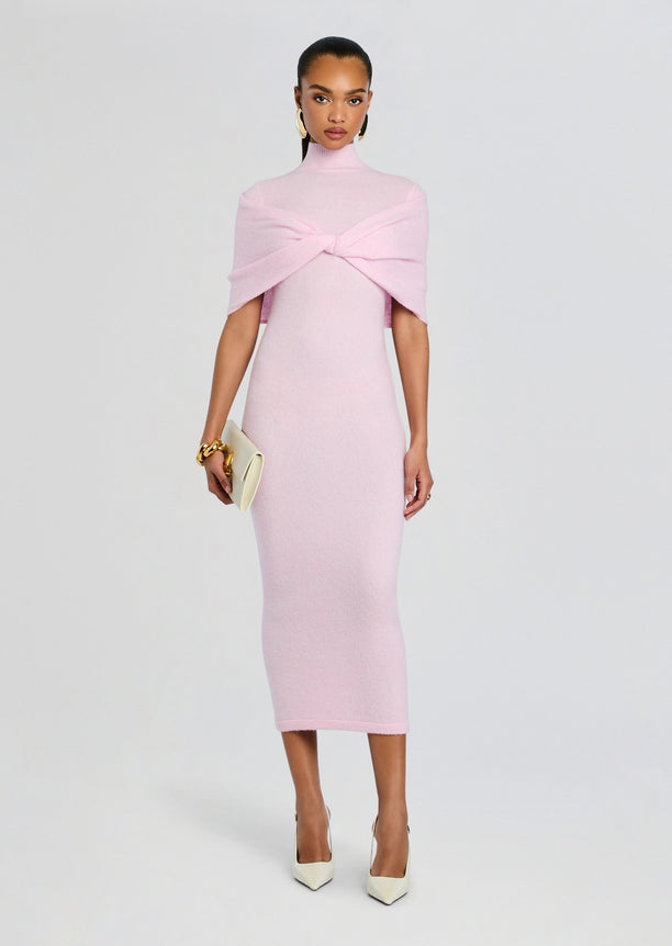 Front view of a model in a pale pink Wisteria Knit Midi Dress featuring a twisted cape draped across the chest.