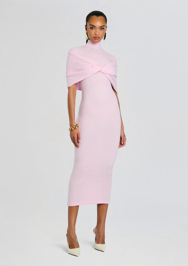 Full-length pink knit midi dress with twisted shoulder wrap and turtleneck, styled with gold jewelry and cream heels.