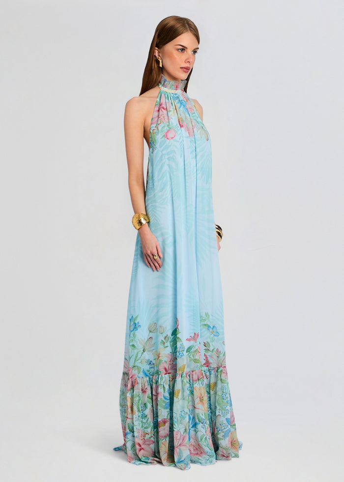 Full length side view of a model wearing a pastel blue floral Francy Dress with a halter neck and tiered ruffled hem media 4 of 6