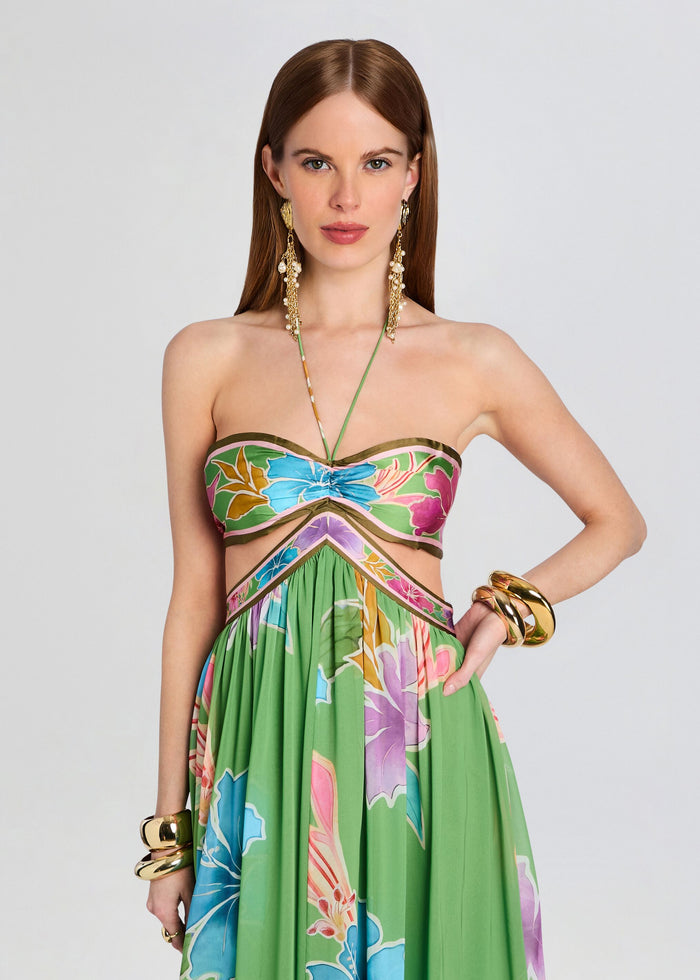 Model wearing the Rabel Dress with a tropical floral bandeau top and green skirt featuring waist cutouts. media 5 of 5