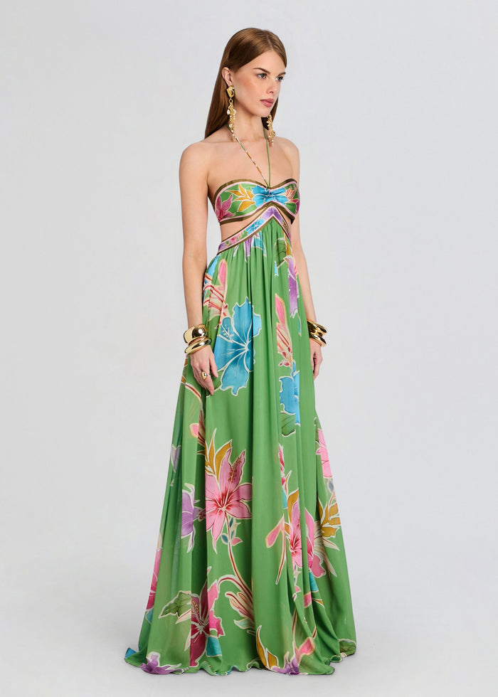 Full length view of the Rabel Dress on model featuring a bandeau floral top and flowing green tropical skirt with halter neck tie. media 3 of 5
