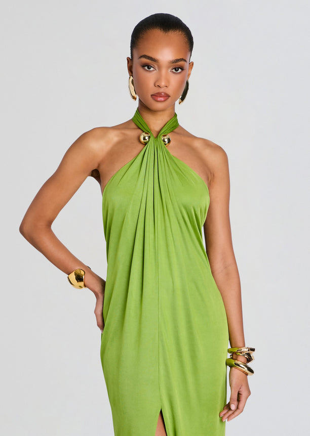Lime green halter neck dress with twisted neckline and draped front, styled with bold gold jewelry.