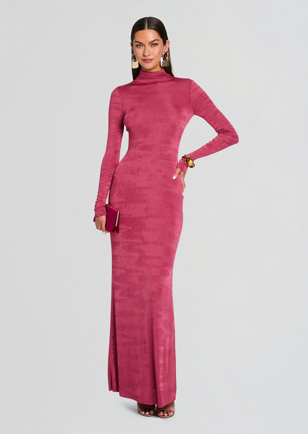 Model in a magenta velvet maxi dress with long sleeves and a turtleneck, holding a magenta clutch