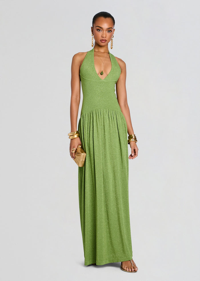 Model wearing a glittery lime green Marcelle Knit Dress with halter neckline and long flowing skirt, accessorized with gold bracelets. media 1 of 6
