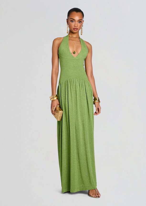 Model wearing a glittery lime green Marcelle Knit Dress with halter neckline and long flowing skirt, accessorized with gold bracelets.