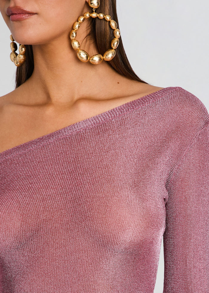 Close up of pink metallic knit fabric at the off shoulder neckline with oversized gold hoop earrings. media 2 of 5