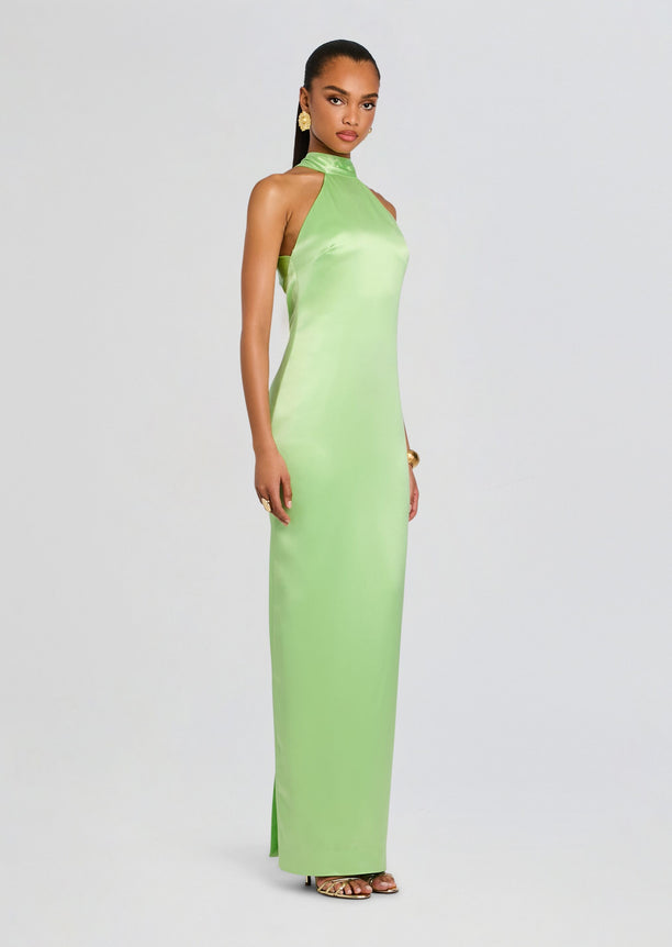 Side profile of a model in a lime green satin maxi dress with a small slit and metallic sandals