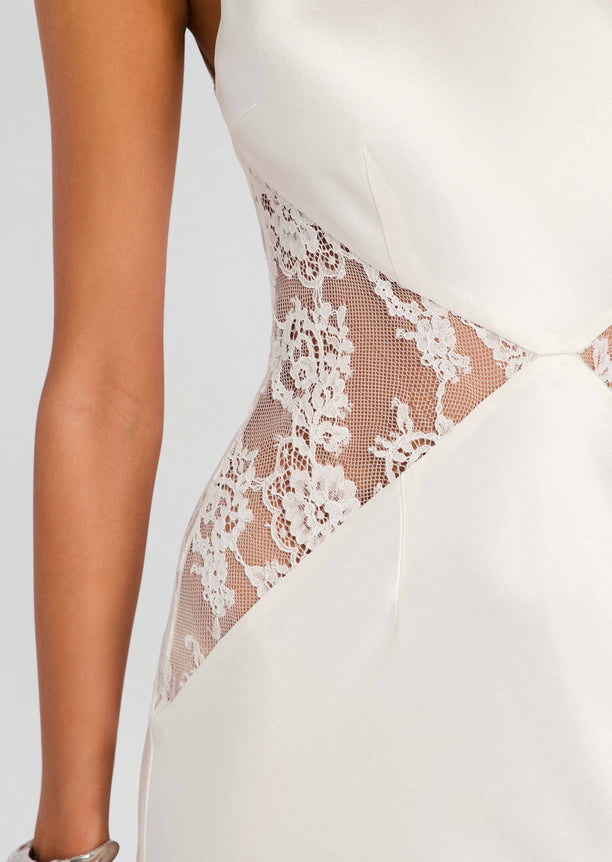 Close up of a white satin dress showing a sheer floral lace side panel