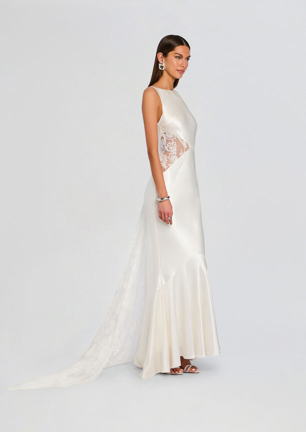 Model wearing white satin Analuisa Lace Dress in side profile with lace panel and long flowing skirt