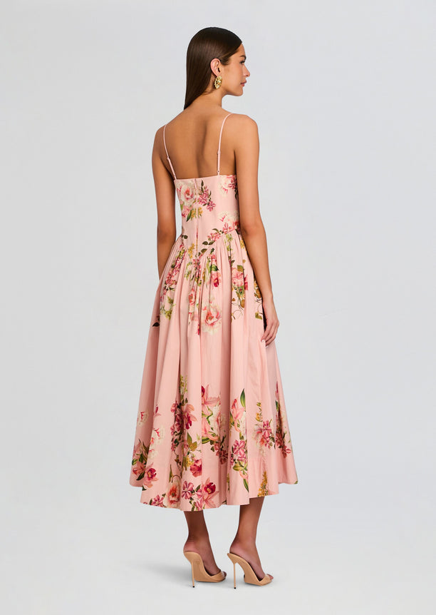 Back view of blush pink Ayla Corseted Midi Dress with floral print and slim straps on a model.