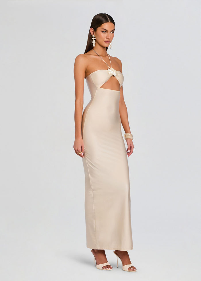 Full-length side view of a model wearing the beige Emeline Maxi Dress with halter neck and waist cutout. media 3 of 5