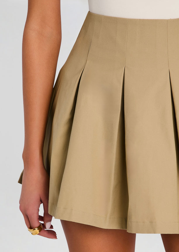 Close up of beige pleated mini skirt showing structured waistband and deep pleats