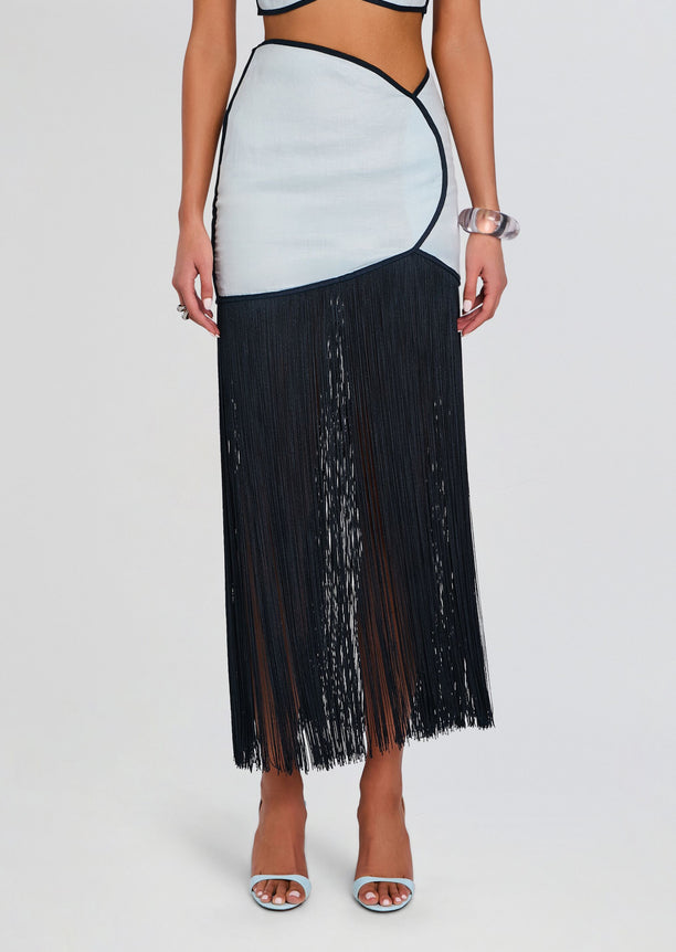Close up of the Joelle Skirt waist showing pale blue fabric with navy piping and the starting point of the black fringe hem.