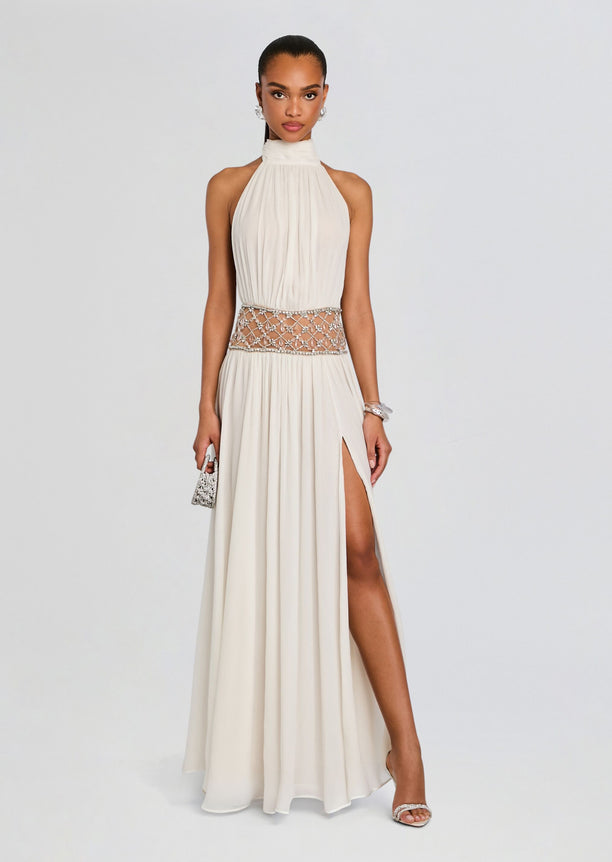 Full-length ivory Kreeli Embellished Dress with a pleated halter bodice, jeweled waist belt, and thigh-high slit.