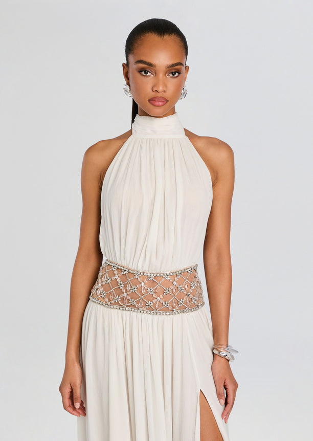 Front view of a cream halter gown with a jeweled lattice waist belt and flowing skirt.