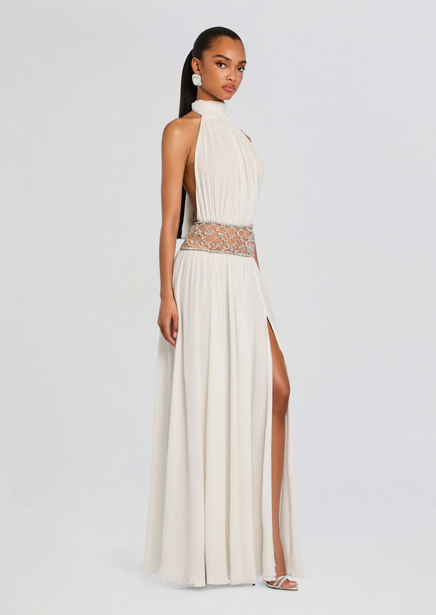 Side view of a model wearing the ivory Kreeli Embellished Dress with a jeweled waist and high side slit.