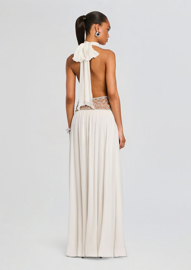 Back view of a cream halter dress with an open back and a jeweled waist belt, floor-length.