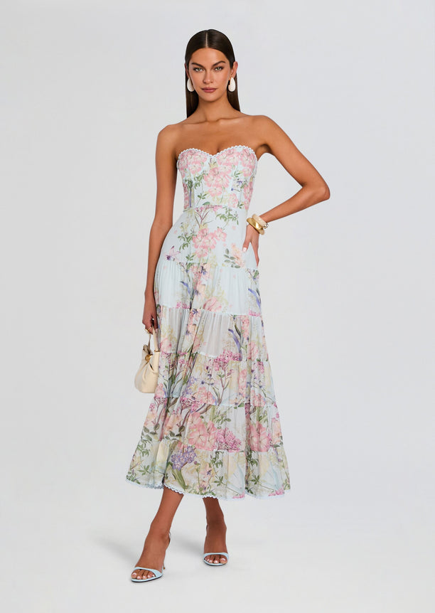 Full-length view of a model in a pastel floral strapless long dress with a lace-trimmed bodice and tiered skirt.