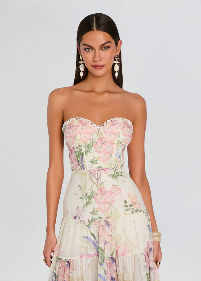 Model wearing a strapless pastel floral long dress with lace trim at the bust and a tiered skirt. media 5 of 5