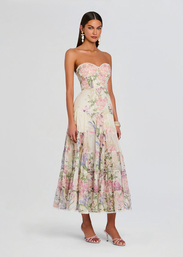 Full-length view of a model wearing a strapless pastel floral long dress with a tiered skirt and lace hem