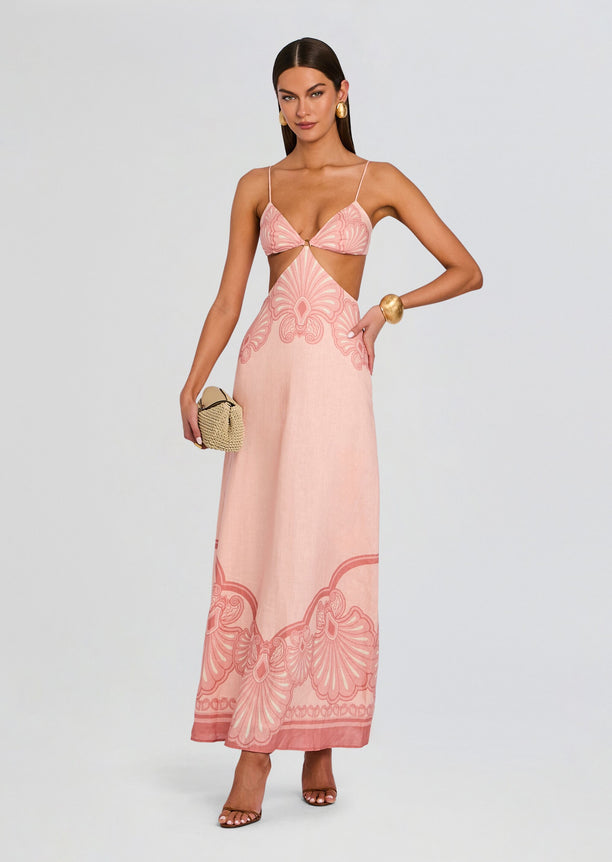 Maya Maxi Dress in blush pink with a waist cutout and central ring, thin shoulder straps, and a bold pink pattern along the hem