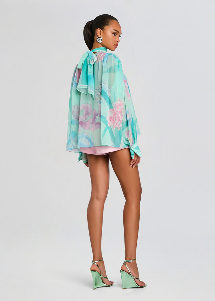 Back view of Olympia Top showing a sheer mint floral blouse draping over pink shorts with a neck tie. media 5 of 7