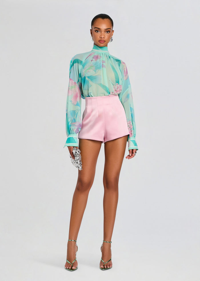 Model wearing Olympia Top a sheer turquoise floral blouse paired with pink high waisted shorts and a jeweled clutch. media 7 of 7