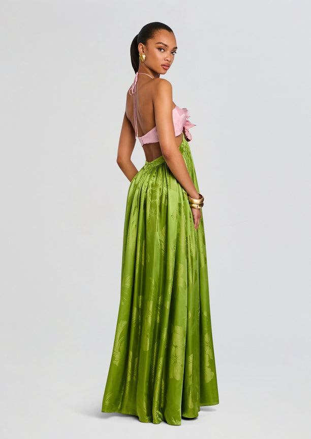 Model in a Prudy Dress with pink top and bright green floral skirt, back view with halter ties