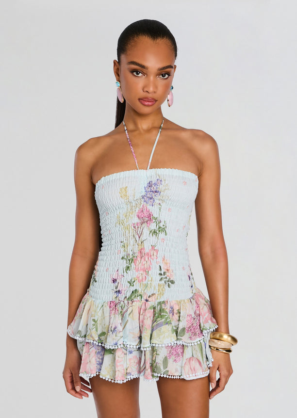 Front view of a model in a light blue floral Cusia Short Dress with smocked bodice and layered ruffle skirt.