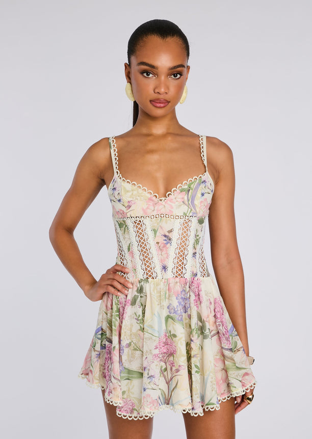 Front view of a floral Gardenia Short Dress on a model with a scalloped lace trim neckline, lace panels, and a tiered floral skirt.