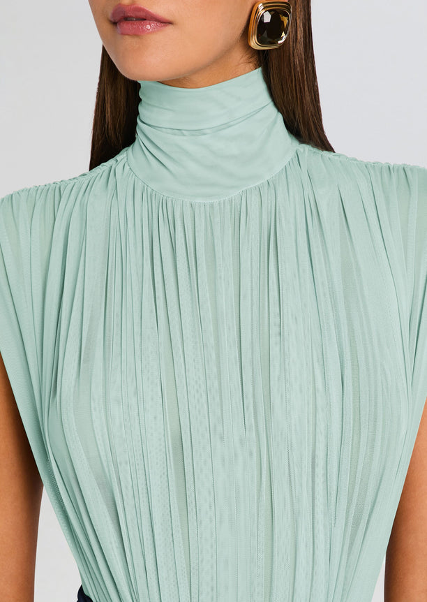 Close-up of mint pleated high-neck top showing textured fabric and soft draping.