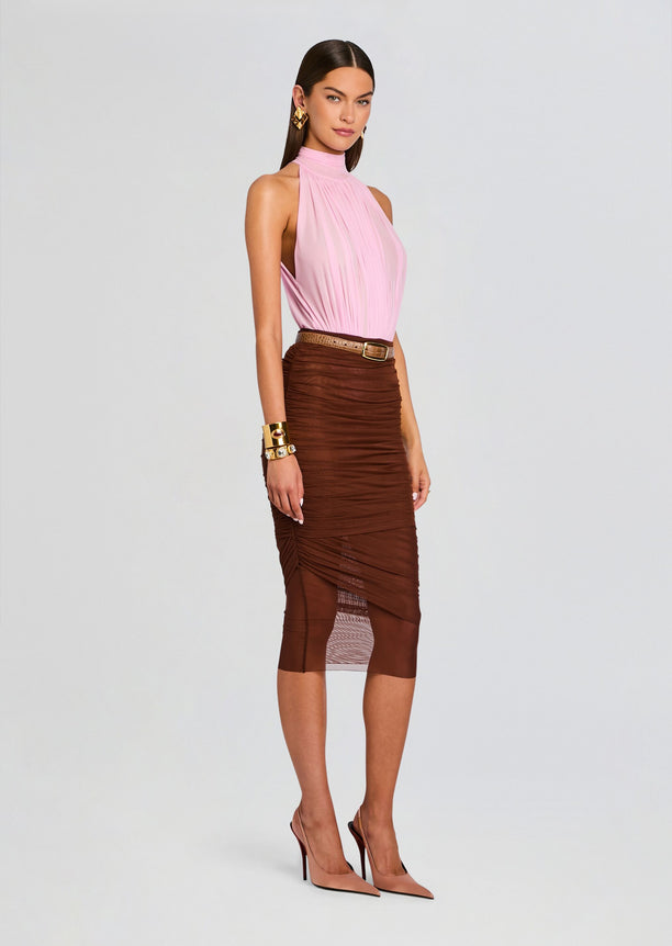 Model wearing a pink pleated halter neck bodysuit tucked into a brown ruched midi skirt with a tan belt and gold jewelry.