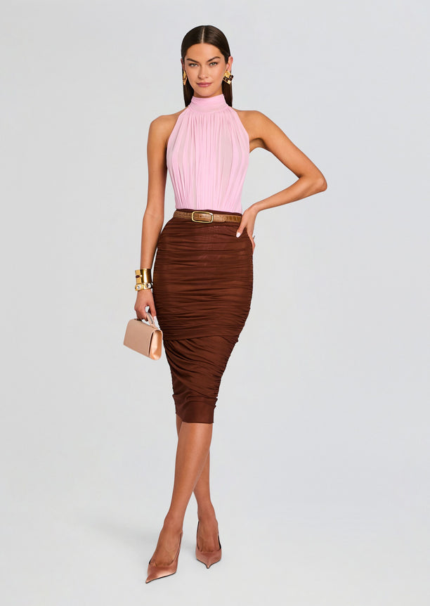 Full-length shot of model in pink halter neck bodysuit and brown ruched midi skirt, nude heels and a beige clutch.