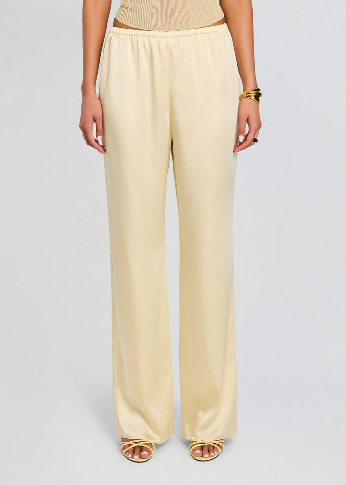 Full length view of pale yellow satin Lillian Pant with elastic waist and wide legs, paired with a knit top and sandals media 1 of 5