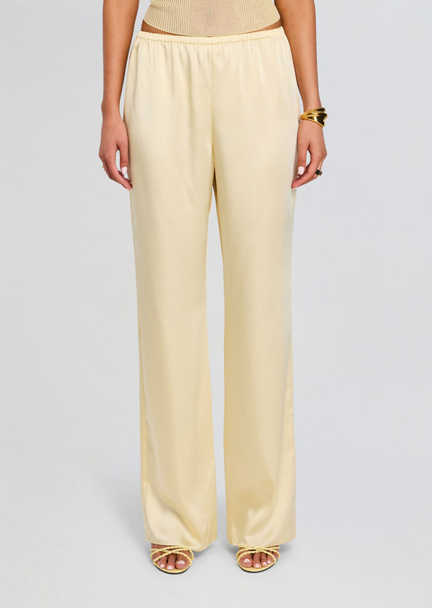 Full length view of pale yellow satin Lillian Pant with elastic waist and wide legs, paired with a knit top and sandals
