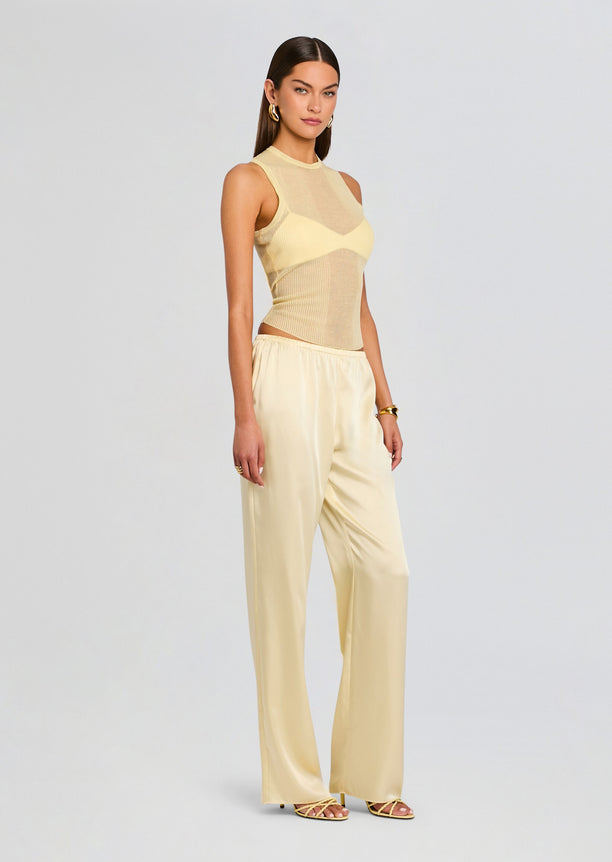 Model wearing pale yellow Jori Rib Knit Tank with sheer panels paired with matching satin wide-leg pants, side view.