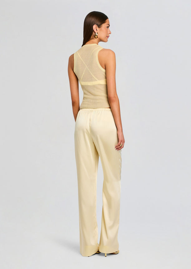 Back view of a model wearing cream satin wide-leg pants with a beige knit top.