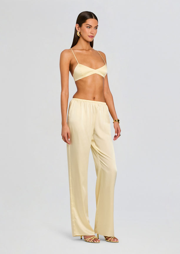 Model wearing pale yellow satin Courtney Bralette with matching wide-leg satin pants.