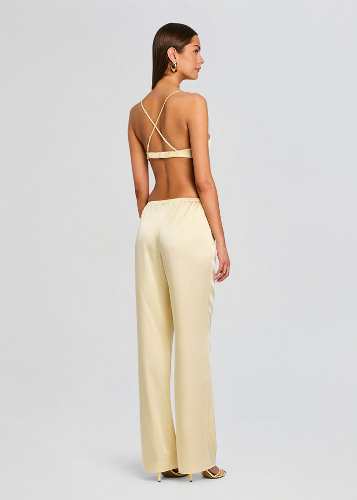 Back view of a model in pale yellow satin Courtney Bralette with crisscross back straps and matching pants. media 5 of 5