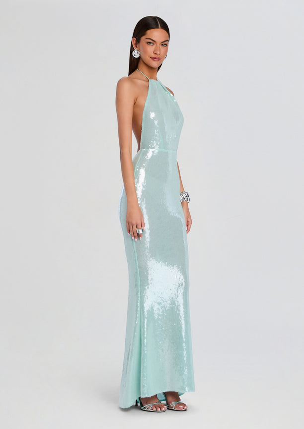 Side view of a model in a mint sequin halter gown with open back and floor-length silhouette