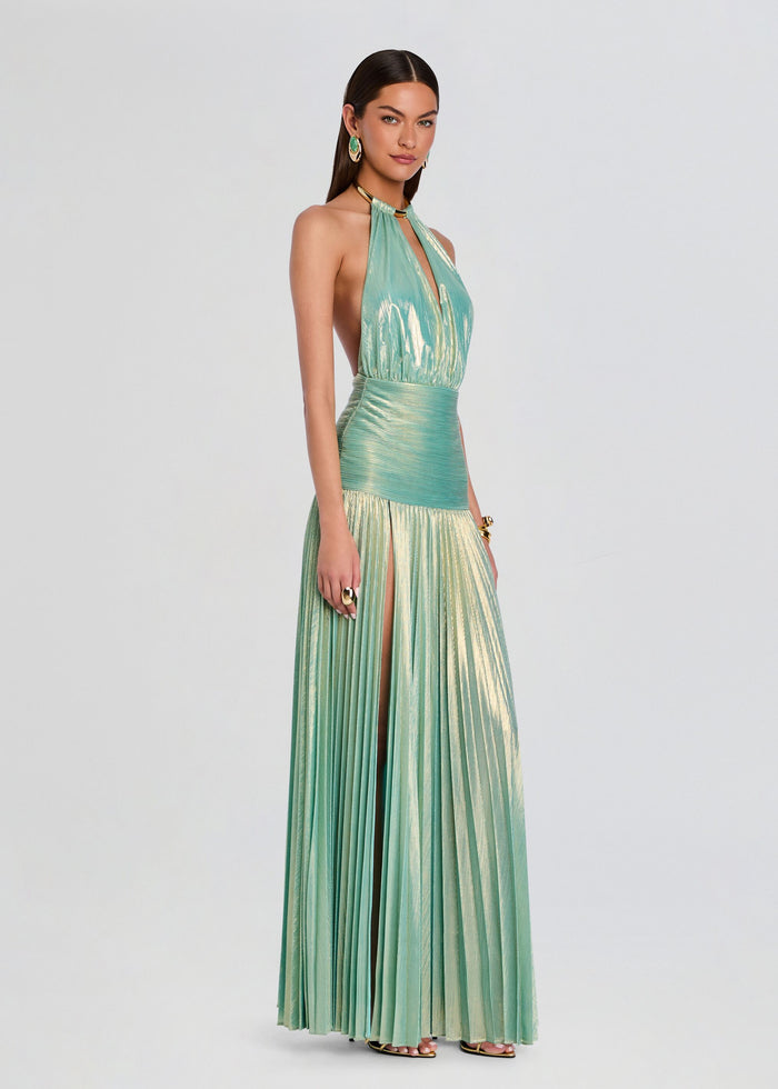 Faelina Dress model wearing teal metallic halter gown with high slit and pleated skirt. media 4 of 6