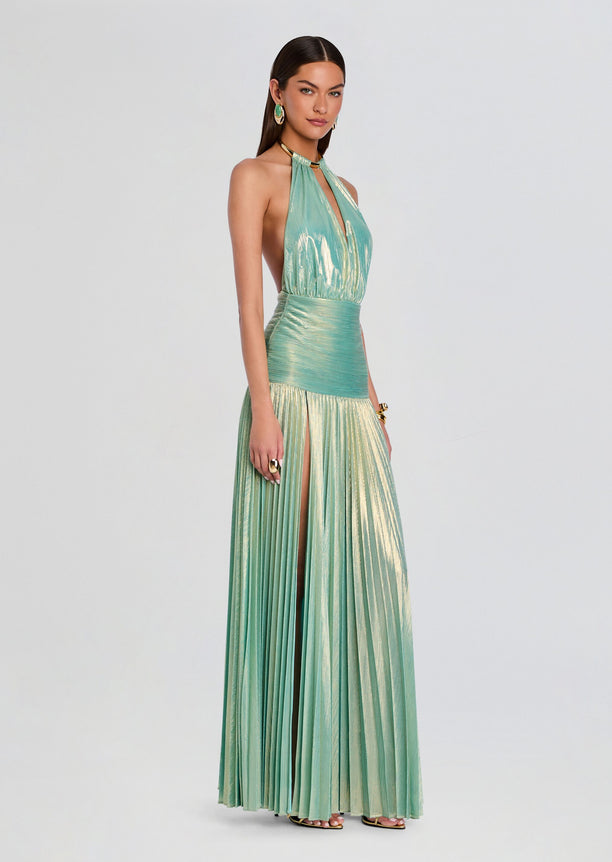 Faelina Dress model wearing teal metallic halter gown with high slit and pleated skirt.
