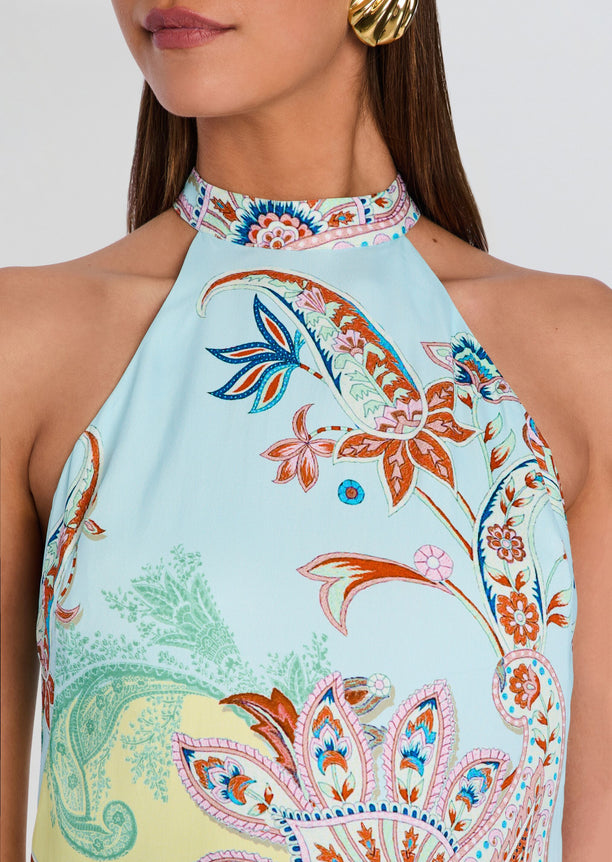 Yuti halter neck mini dress close up showing pastel blue fabric with vibrant paisley floral print.